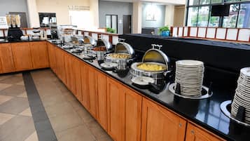 A buffet setup with various food items and a coffee station.