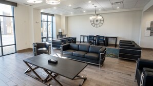 Eine großzügige Lobby mit modernem Design, ausgestattet mit einer großen Couch, mehreren Tischen und einer großen Wanduhr.