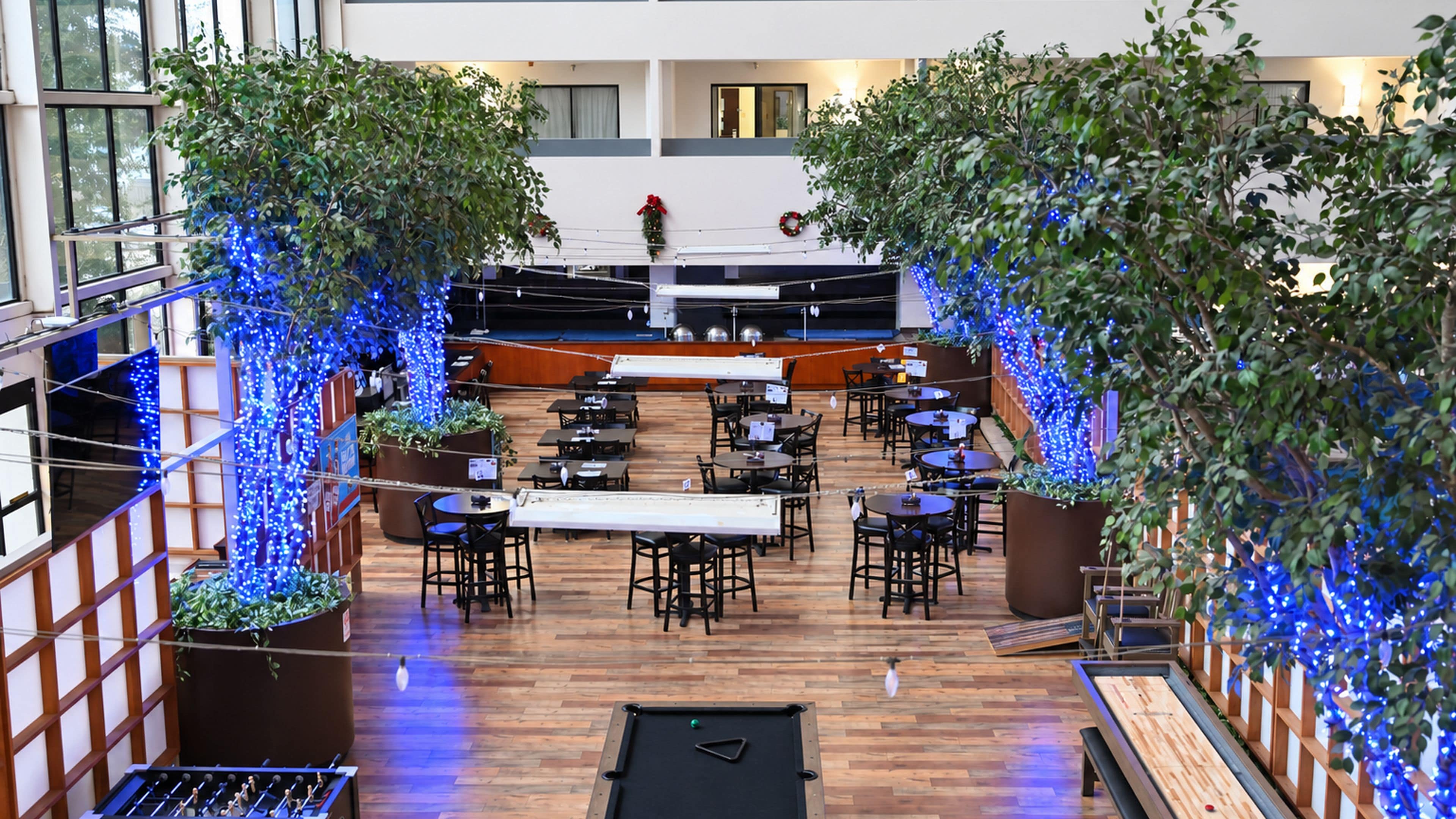 An indoor dining area with tables and chairs, a pool table, and decorative plants.