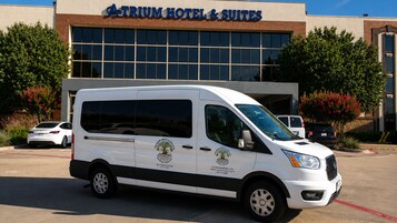 Una camioneta blanca estacionada frente al Hotel & Suites Atrium, con vista clara a la fachada del edificio.