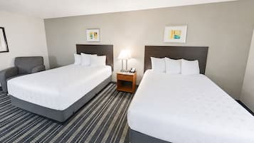 Une chambre d’hôtel avec deux lits, une table de chevet avec une lampe et des œuvres d’art accrochées aux murs.