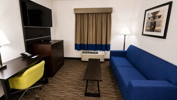 Habitación de hotel con escritorio, silla, sofá y un cuadro en la pared.