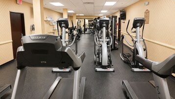 Un gimnasio con varias máquinas de cardio, incluyendo cintas de correr y bicicletas estáticas, dispuestas en fila.