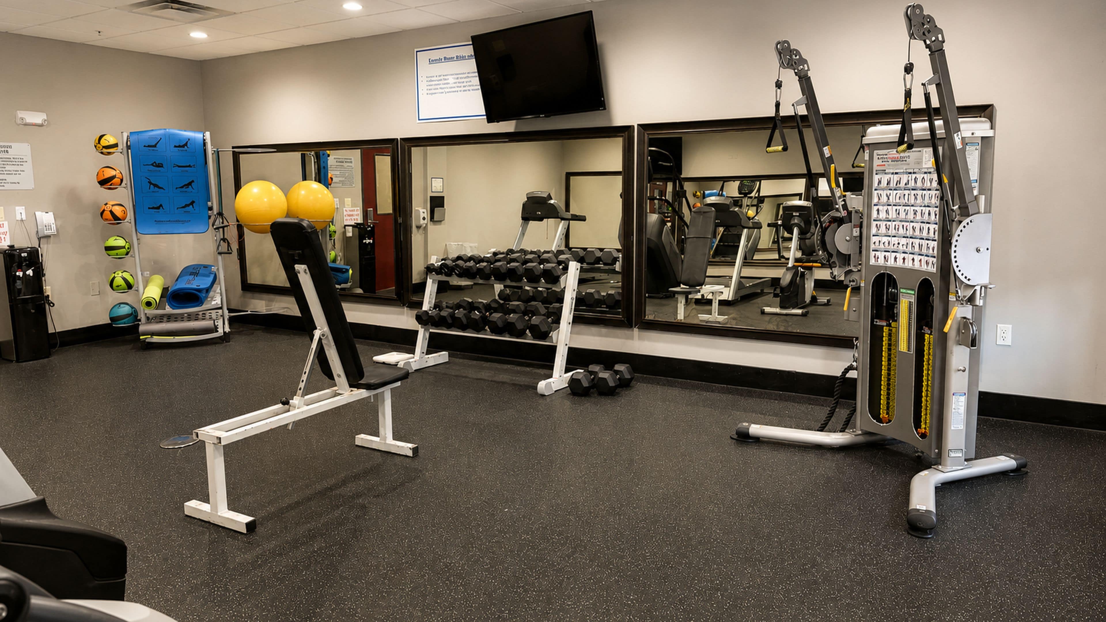 A gym with exercise equipment, a television, and a mirror.