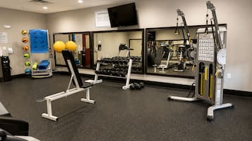 A gym with exercise equipment, a television, and a mirror.