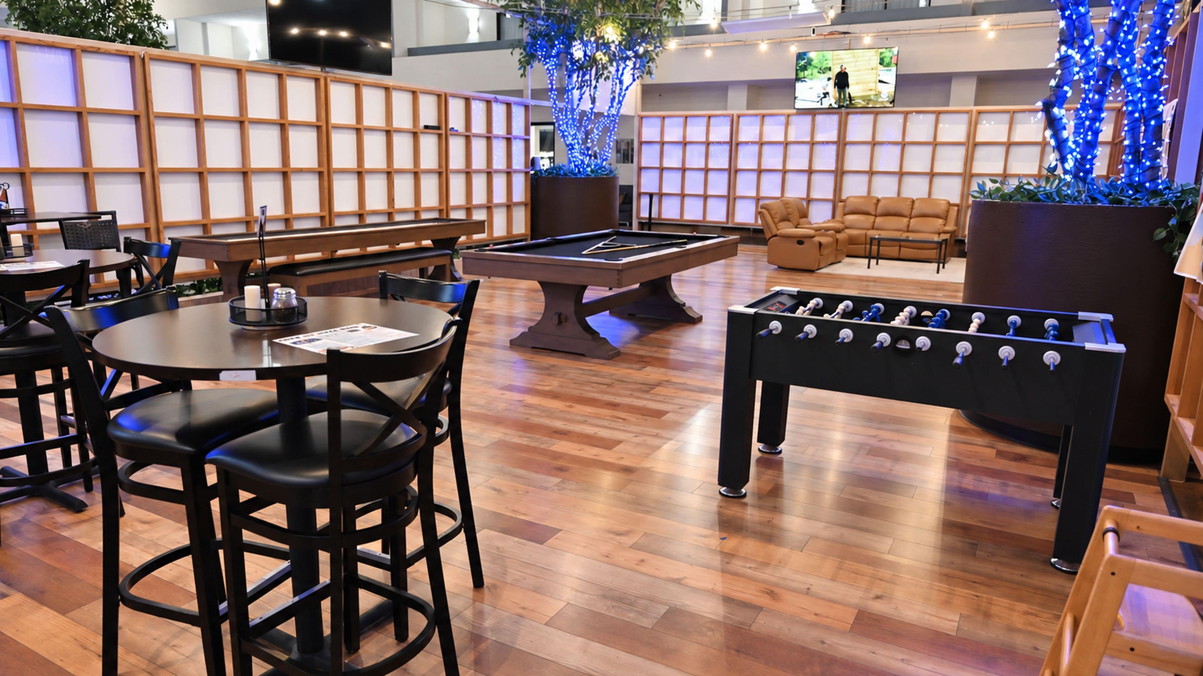 A billiards table, seating area, and a foosball table in a lounge setting.