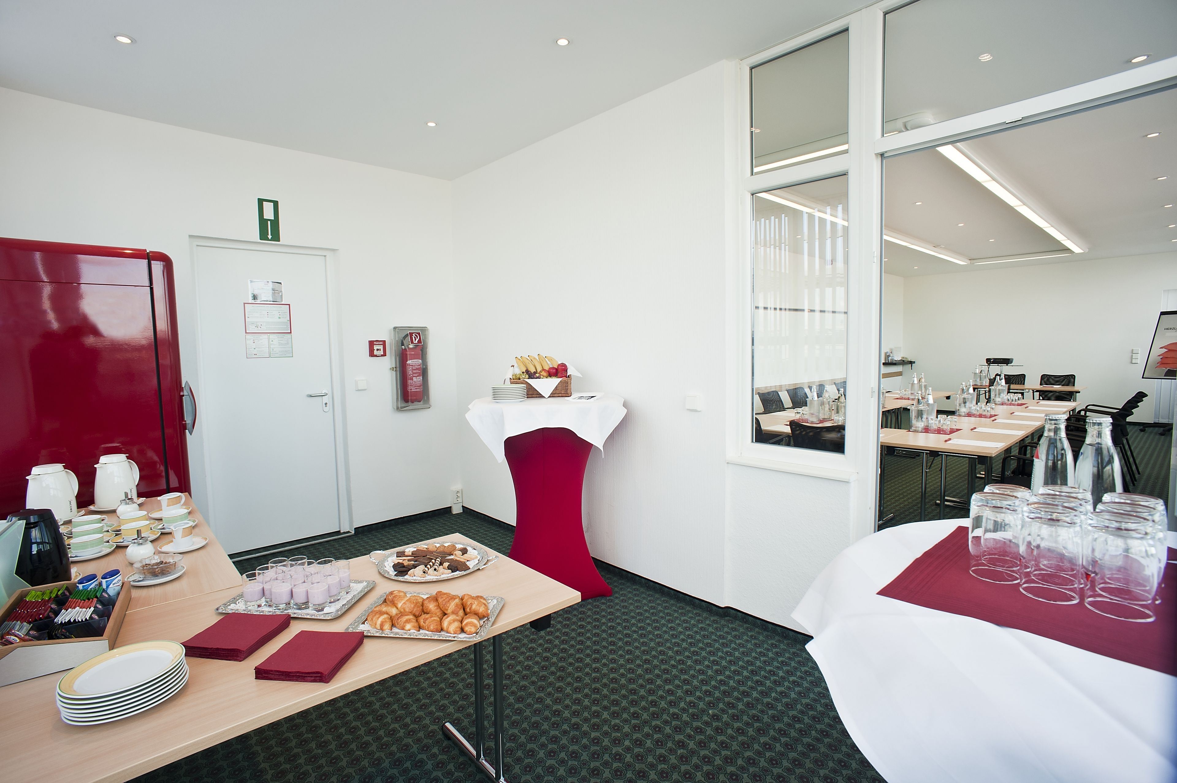 A hotel room with a dining area featuring a table set with plates, glasses, and a variety of food items.
