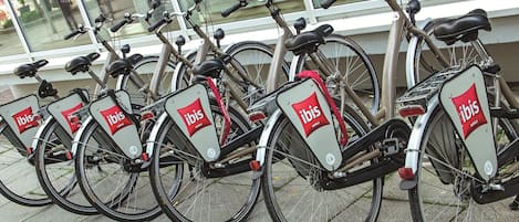 Una fila de bicicletas con la marca 'ibis', estacionadas frente a un edificio con grandes ventanales.