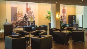 A lobby with dark leather sofas, a reception desk, and a large wall mural. - ibis Dresden Zentrum (Dresden)