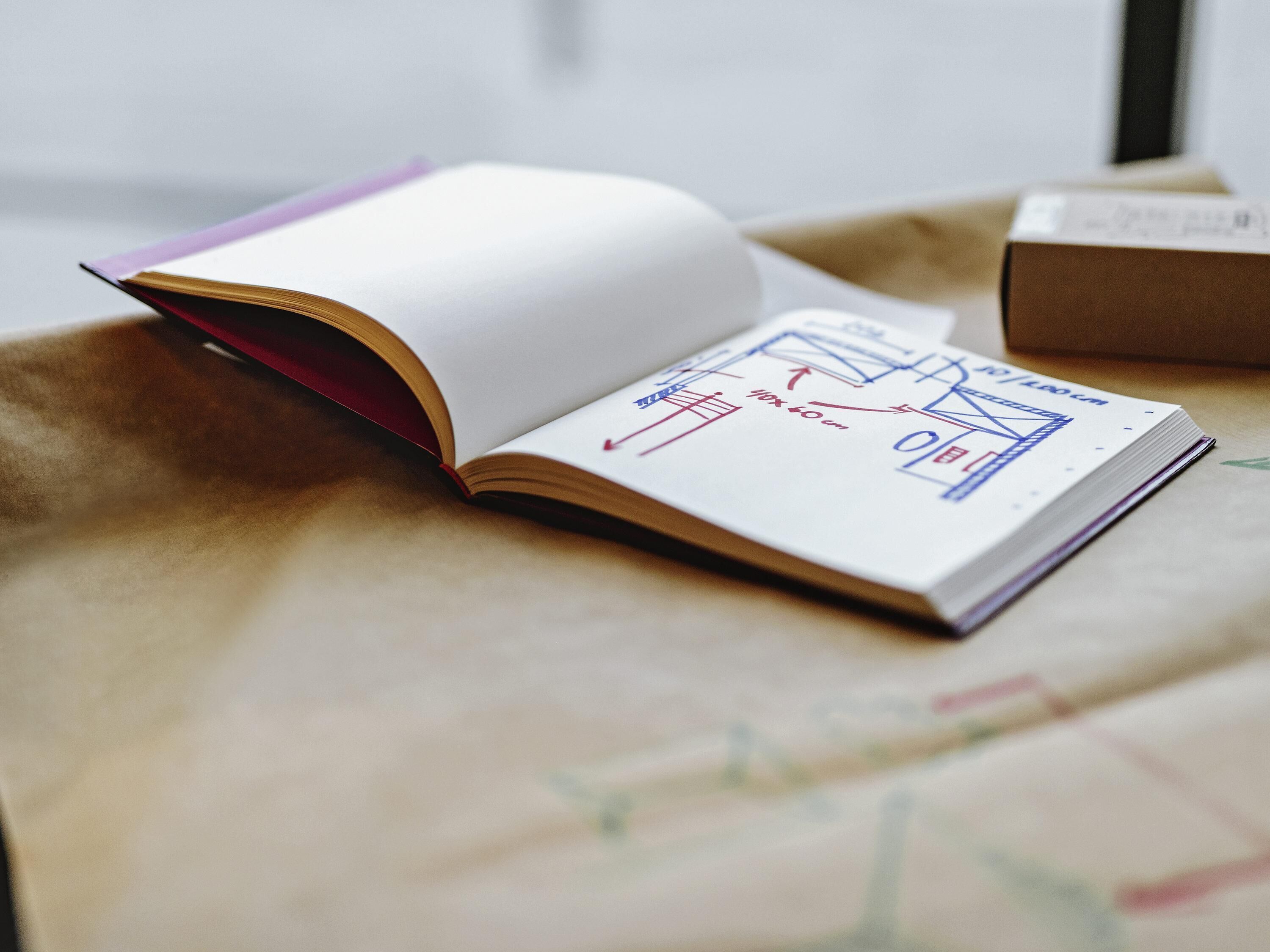 An open book with architectural drawings on a beige surface.