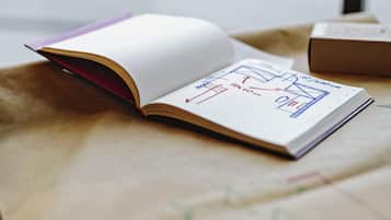 An open book with architectural drawings on a beige surface.