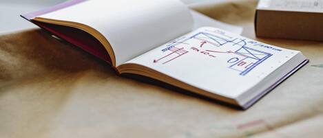 Un libro abierto con dibujos arquitectónicos sobre una superficie color beige.