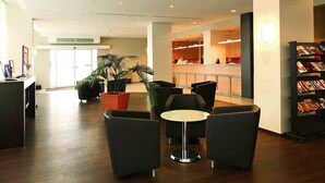 A modern lobby with a reception desk, seating area, and a magazine rack. - ibis Dresden Zentrum (Dresden)