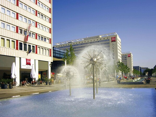 A hotel with a fountain in the courtyard, a modern building with a glass facade, and a sign for the ibis hotel. - ibis Dresden Zentrum (Dresden)