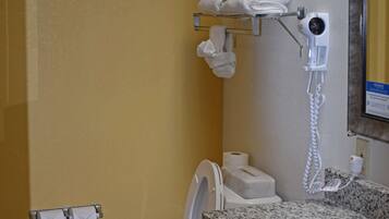 Um banheiro com bancada de mármore, porta-toalhas com toalhas, secador de cabelo, suporte para papel higiênico e secador de mãos.