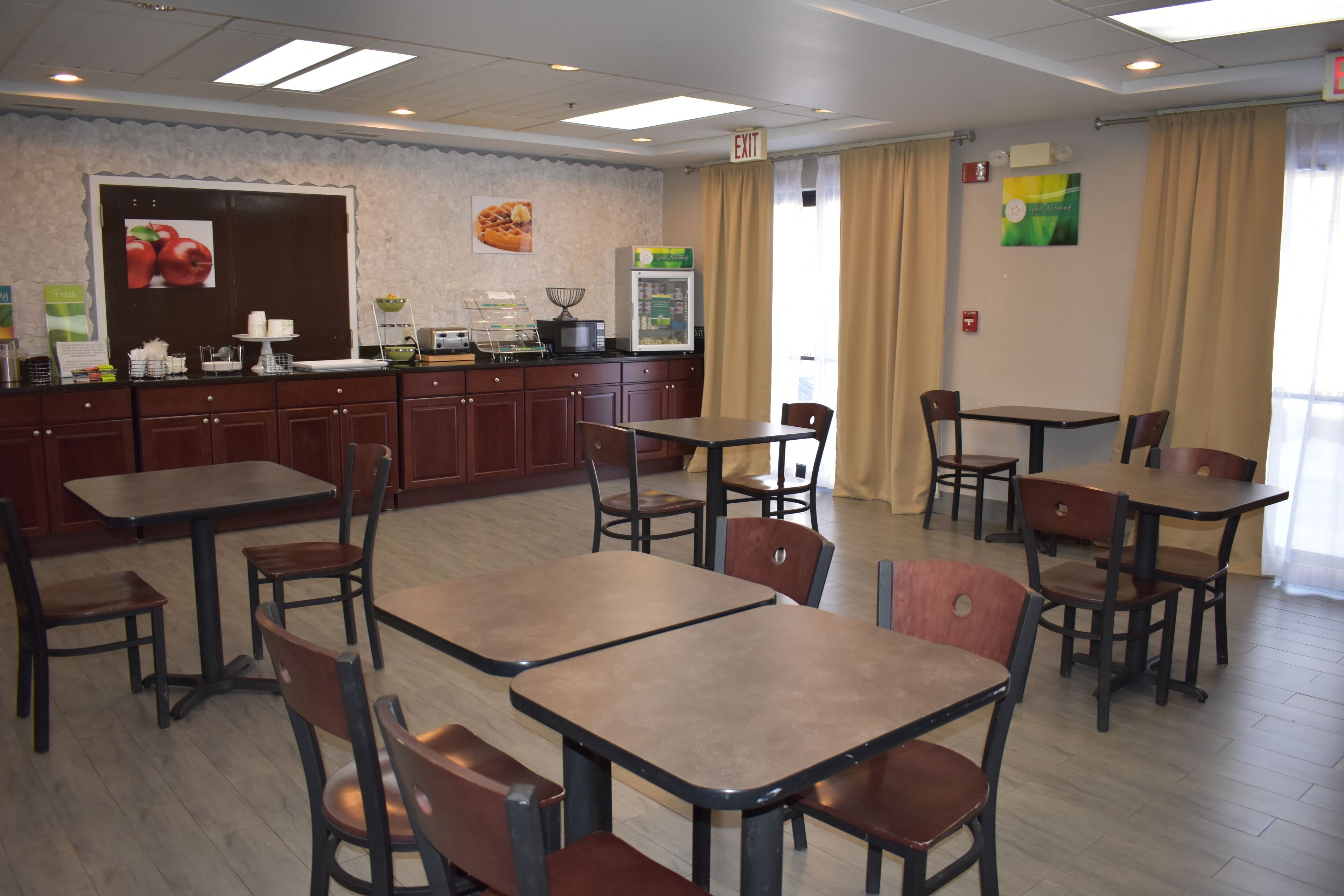 A restaurant with multiple tables and chairs, a buffet counter, and a refrigerator.