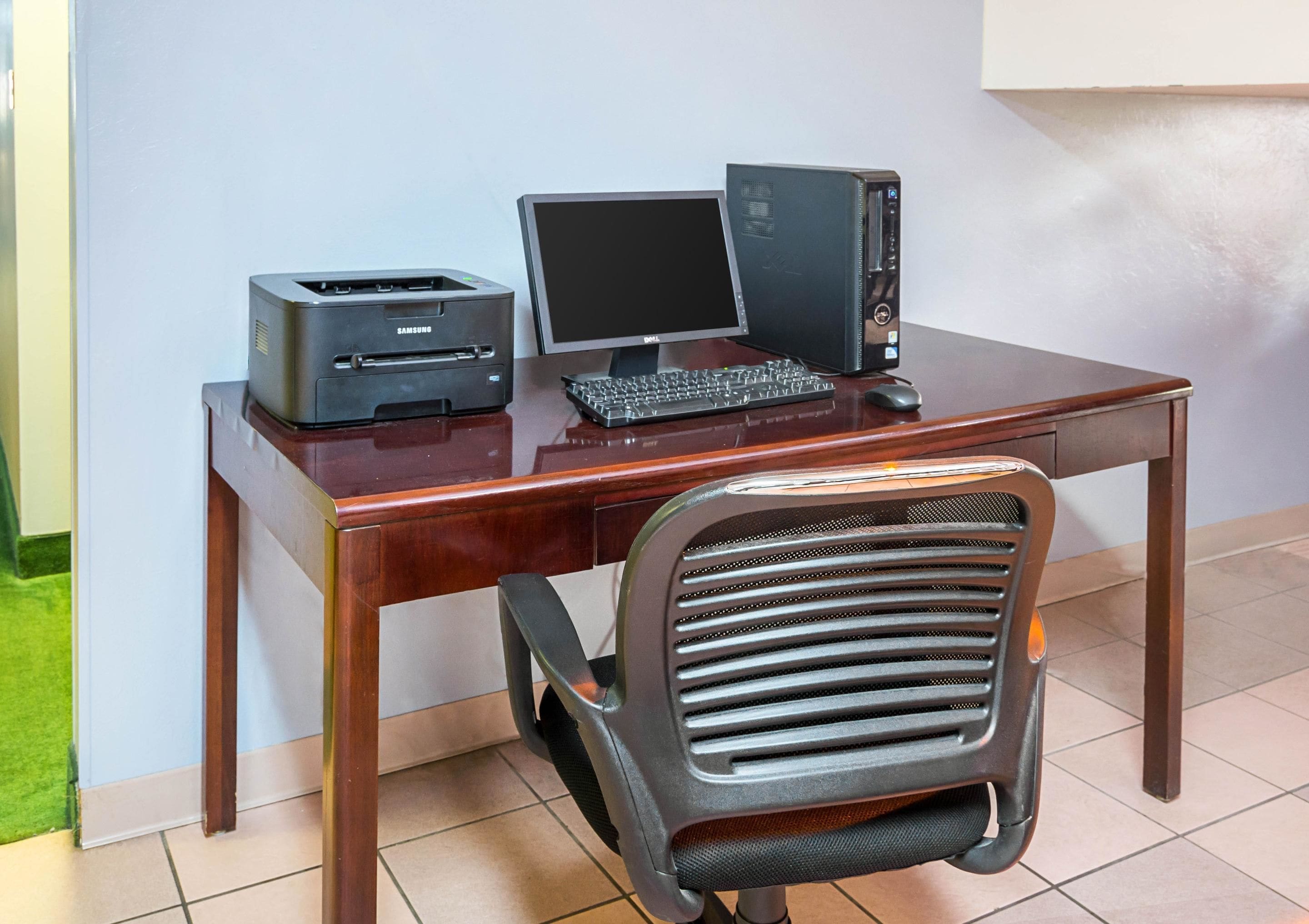 Escritorio de madera con una computadora de escritorio, un monitor e impresora.