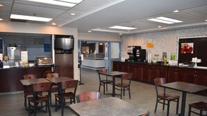 Un ristorante con diversi tavoli e sedie, una zona cucina e un bancone con varie pietanze e bevande.