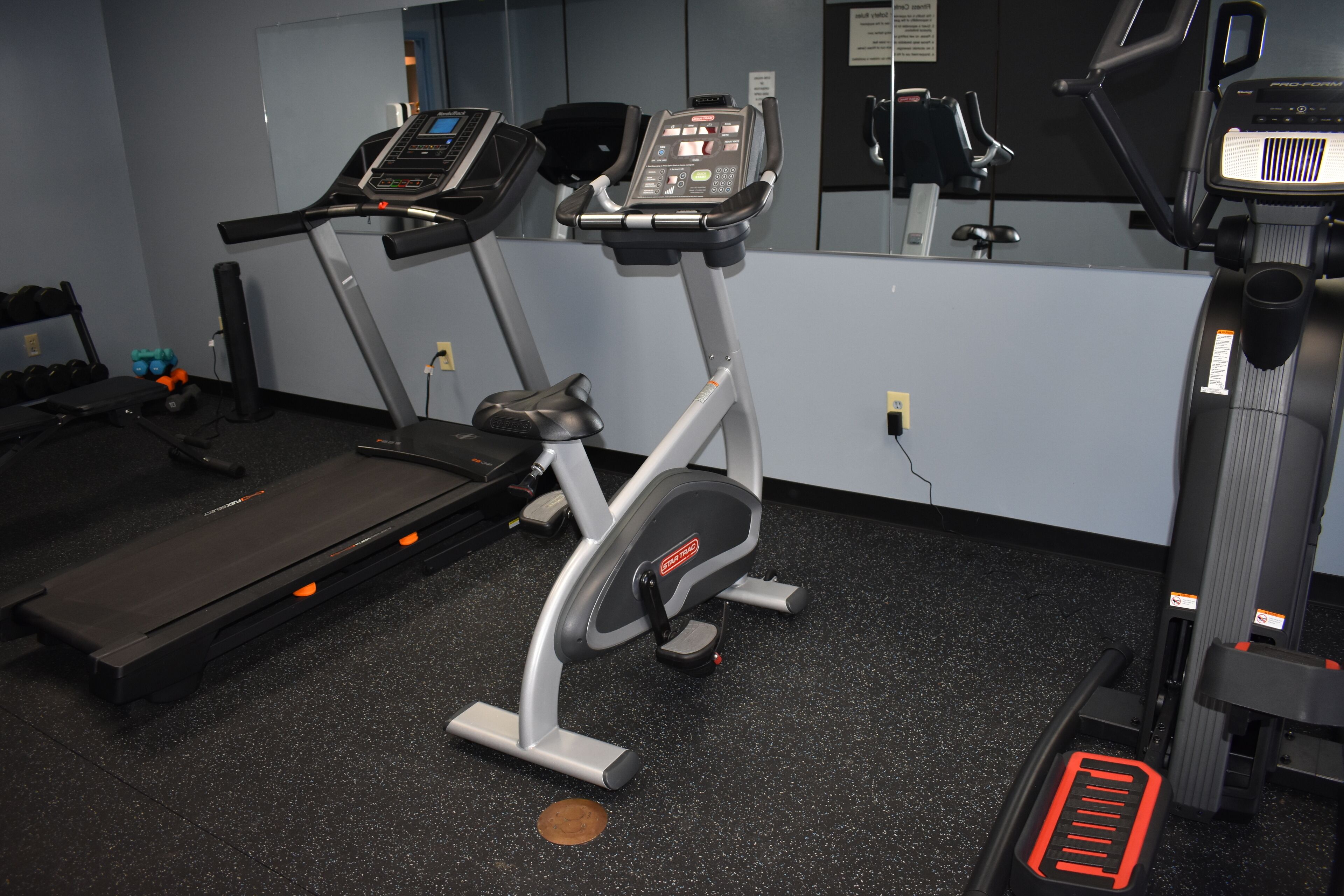 A gym with treadmills, an elliptical, and a bench.