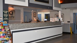Una reception di hotel con un cartello per telefono di cortesia per gli ospiti, un quadro incorniciato a parete e un bancone con diversi oggetti.