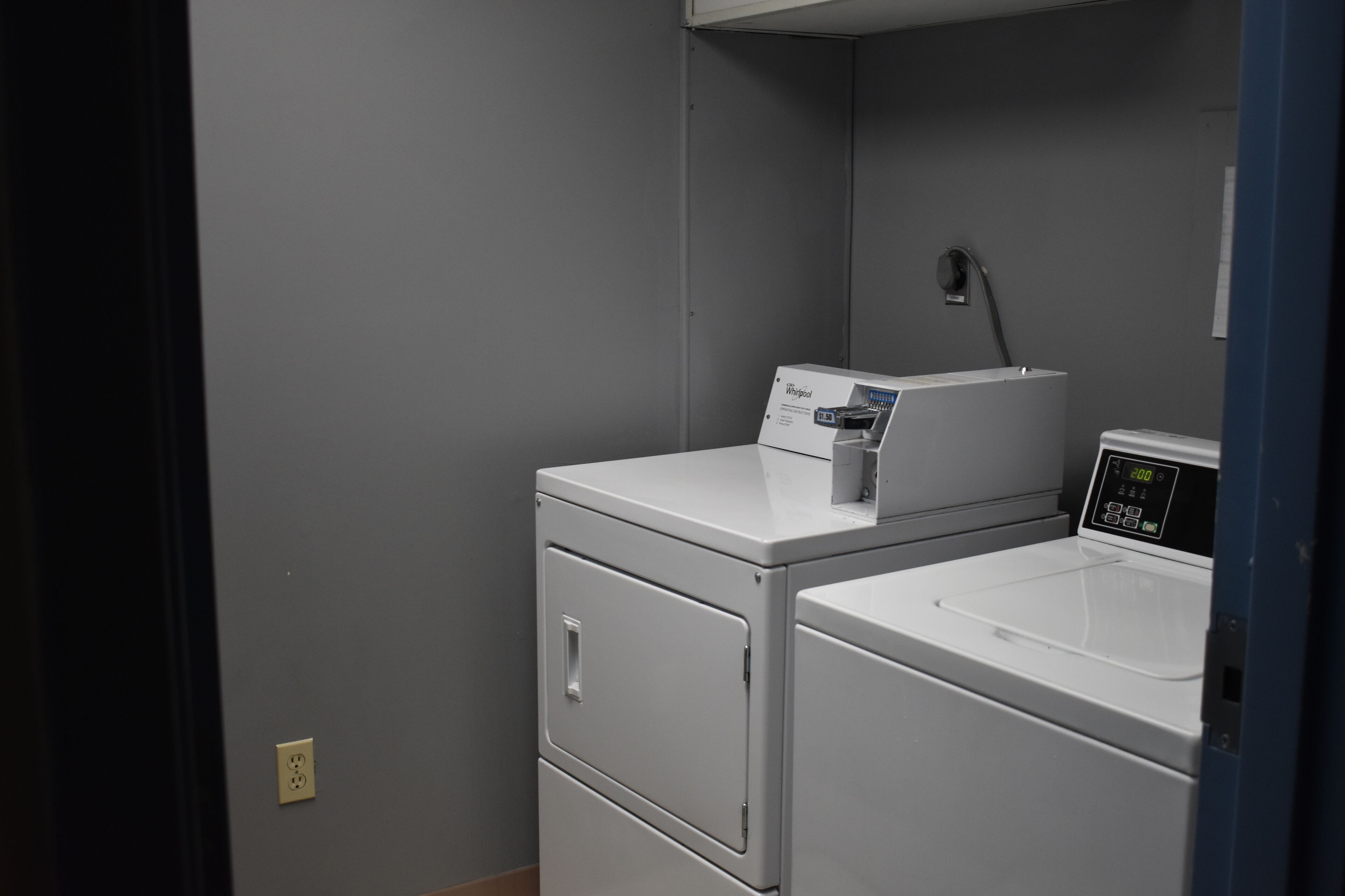 A laundry room with two stacked washers and a dryer, a control panel, and a water heater.