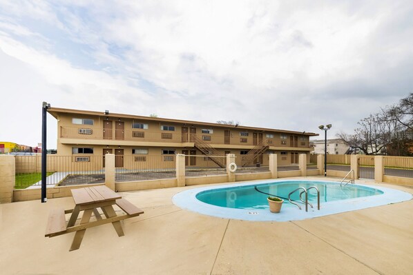 Ein Hotel mit Schwimmbad, Picknicktisch und einem eingezäunten Bereich.