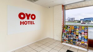 Hotellin aula, jossa on suuri «OYO HOTEL» -kyltti, ilmoitustaulu matkailuesitteineen ja näkymä rakennuksiin ikkunasta.