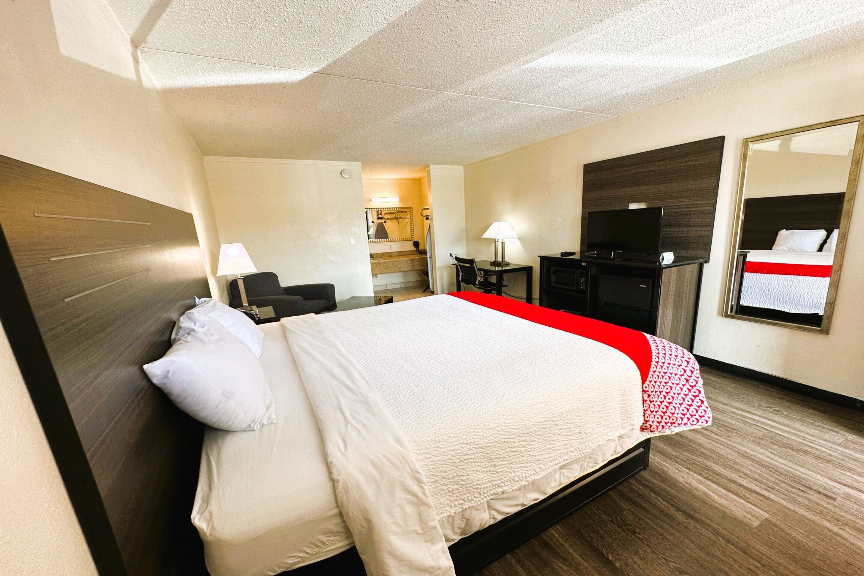 A hotel room with a bed, a desk, a TV, and a mirror.
