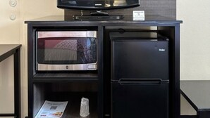 Pieni, mutta toimiva keittiönurkkaus, jossa on mikroaaltouuni, jääkaappi ja televisio.