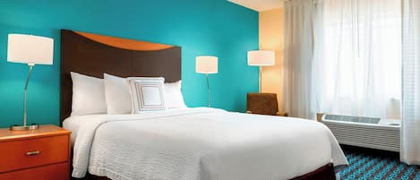 A hotel room with a bed, a nightstand, two bedside lamps, a chair, and a window with curtains.