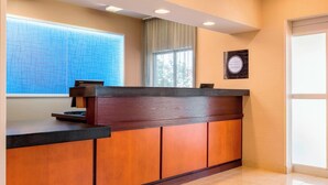 A reception desk with a wooden finish, a large window with a view, and a plaque on the wall. - Fairfield Inn & Suites Abilene (Abilene)