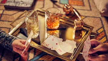 A tray with a glass of water, a candle, and playing cards on a patterned carpet.
