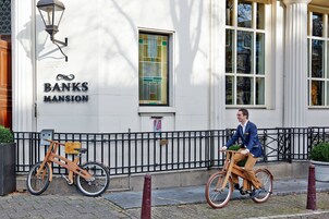 Un edificio con un letrero que dice "Banks Mansion" y una persona andando en bicicleta.