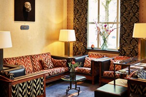 Un salón bien amueblado con sofás estampados, una mesa de centro de cristal y un jarrón con flores.