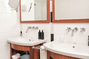 Un baño con dos lavamanos, un espejo y un perchero para toallas.
