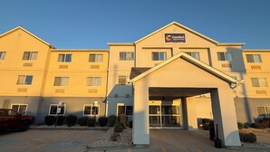 Un hôtel à plusieurs étages, doté d’une entrée principale, d’une enseigne indiquant qu’il s’agit d’un Comfort Inn & Suites, et d’un parking situé à l’avant.