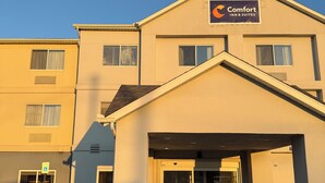 Un bâtiment de la chaîne Comfort Inn & Suites, doté d’une entrée abritée, d’un panneau indiquant les places de stationnement réservées aux personnes handicapées et surplombant un ciel dégagé.