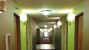 A hotel hallway with a patterned carpet, doors on both sides, and overhead lighting. - Holiday Inn Express & Suites Jackson Downtown - Coliseum by IHG (Jackson)