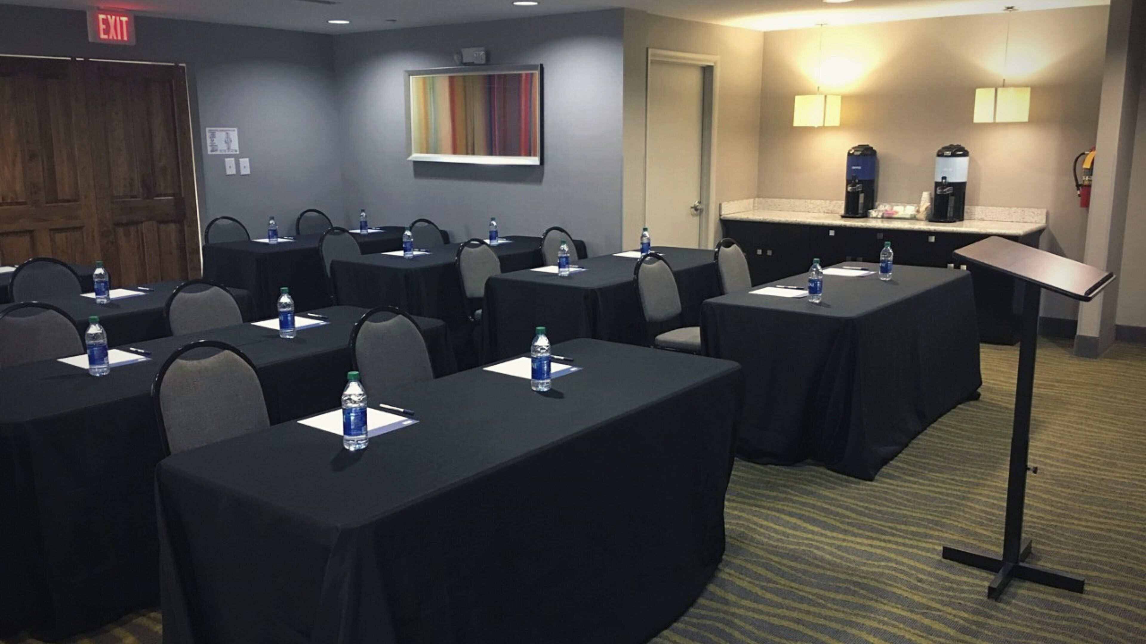 A conference room with tables, chairs, water bottles, and a coffee station.
