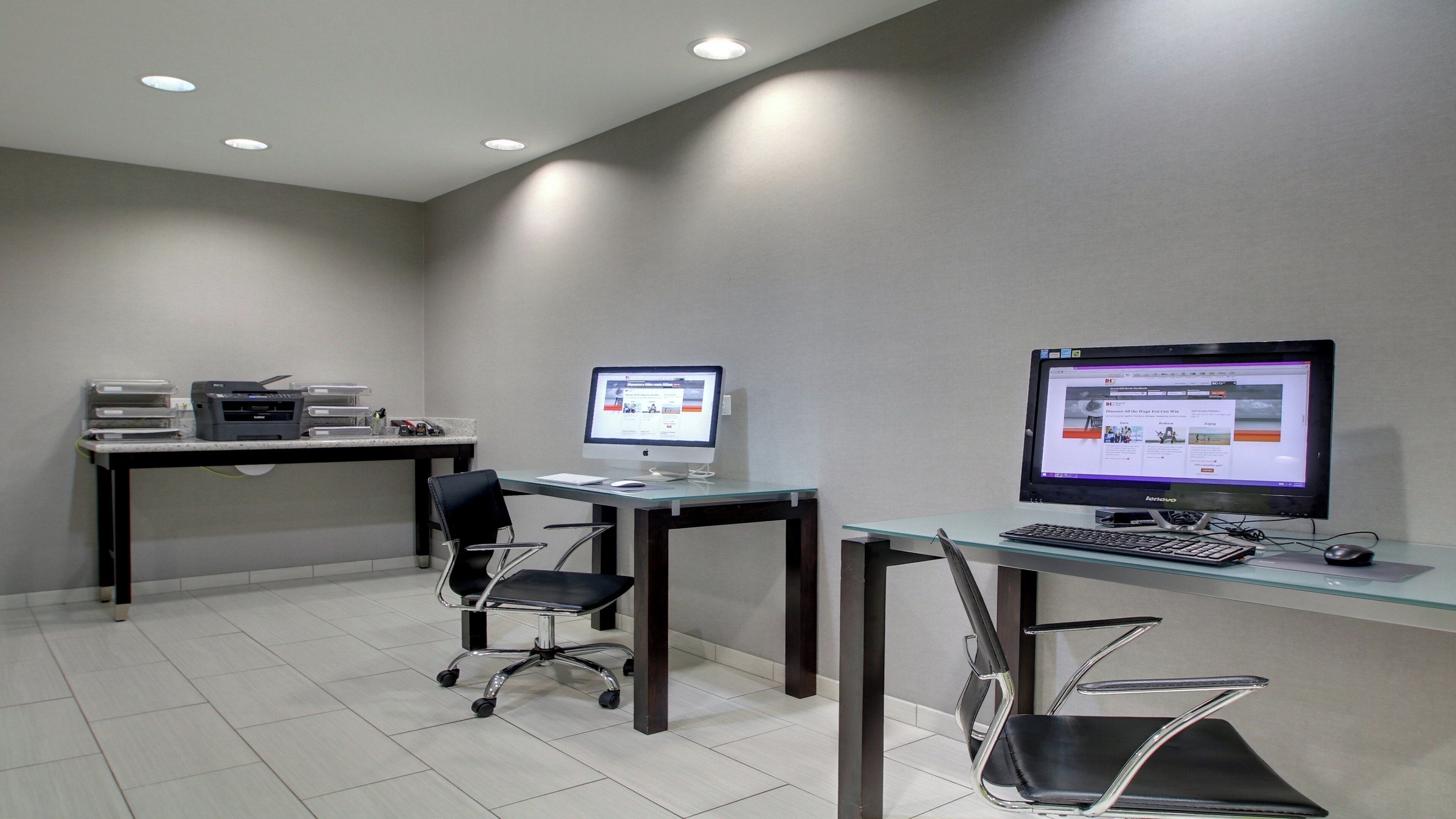 Un espace de bureau moderne comprenant deux bureaux, chacun équipé d’un ordinateur et d’une chaise, et une imprimante placée sur le bureau de gauche.