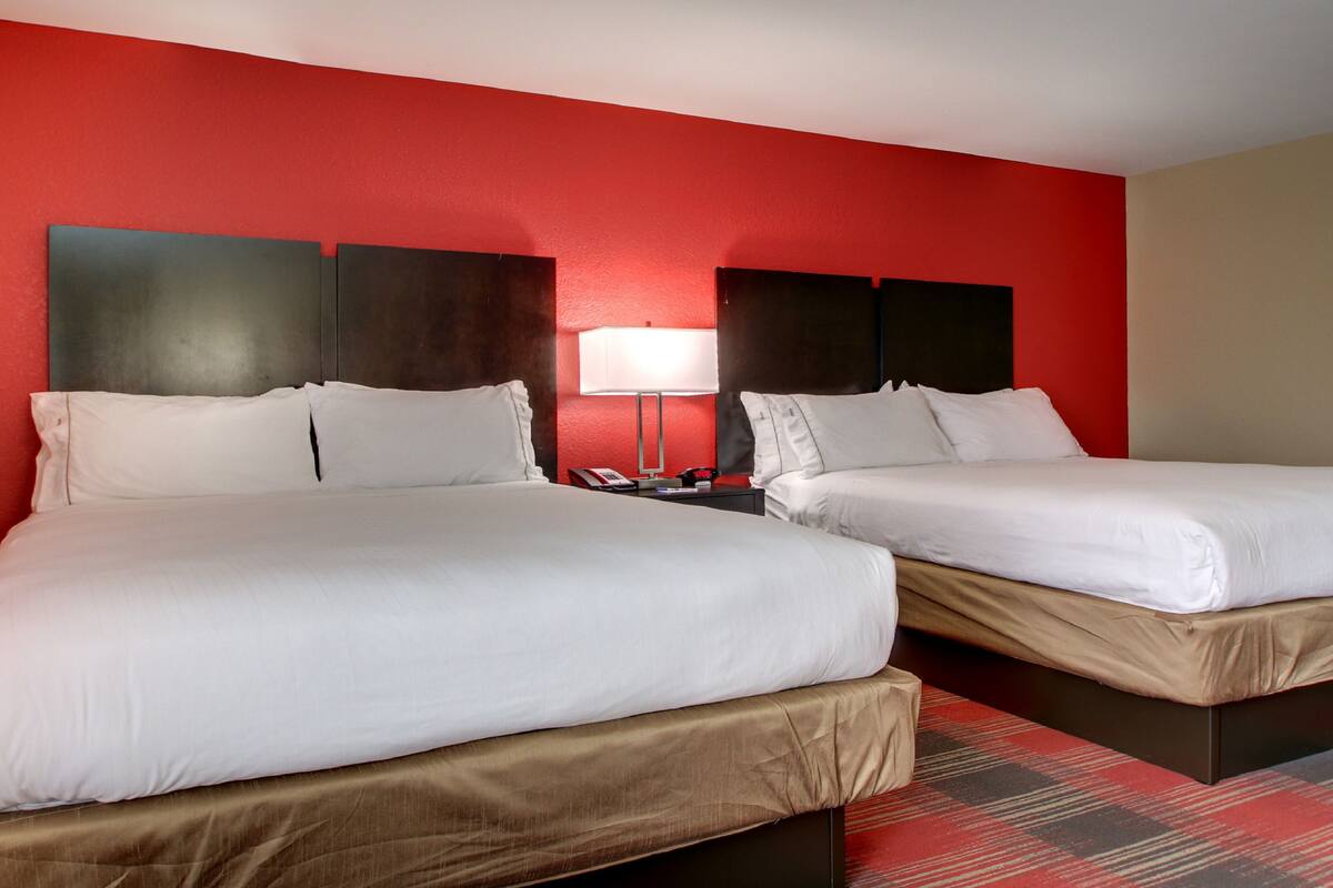 Two single beds with white linens in a room with red and beige walls.