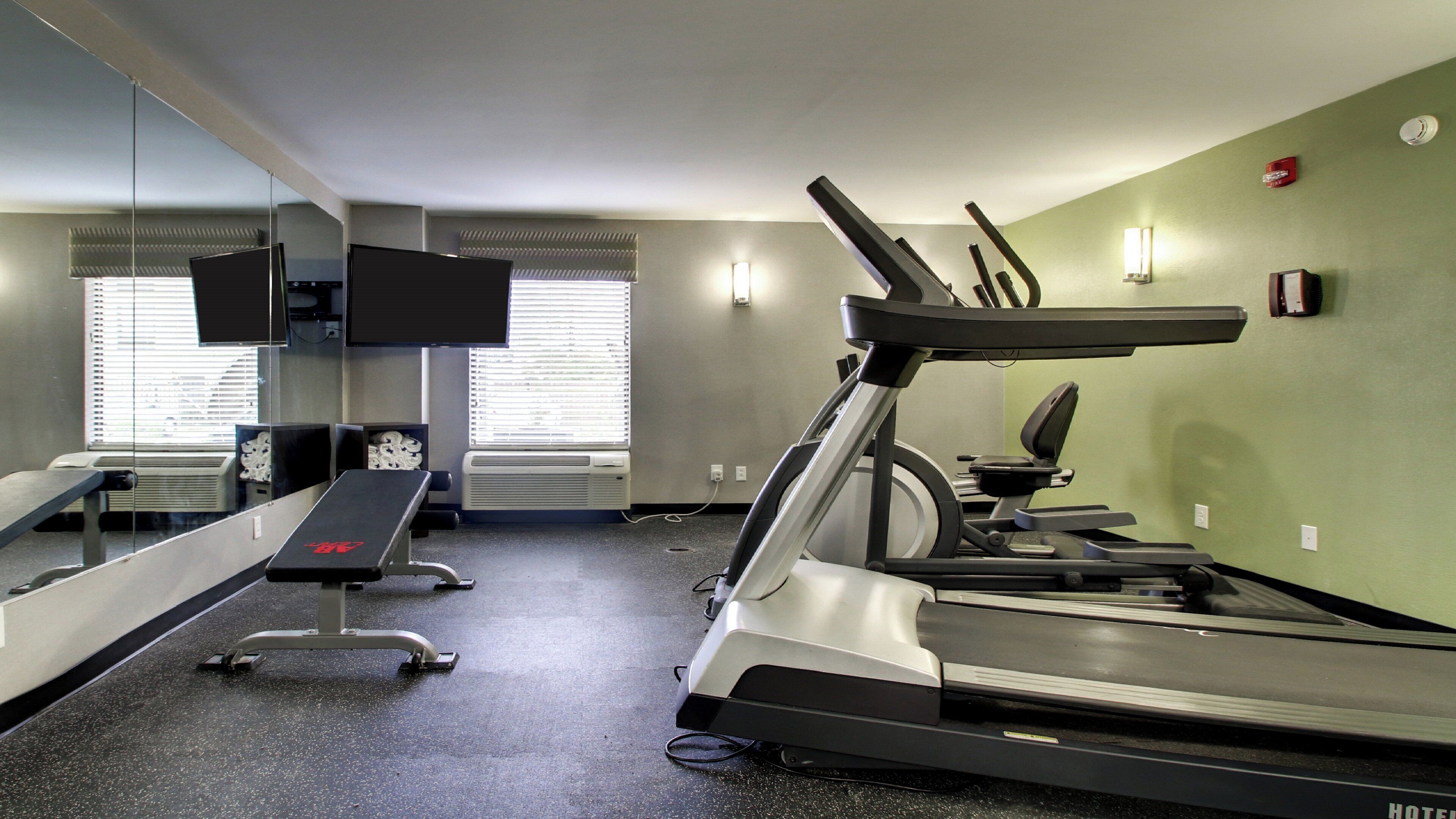 A gym with treadmills, a bench, and a television.