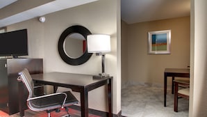 A hotel room with a desk, chair, TV, lamp, and artwork on the wall. - Holiday Inn Express & Suites Jackson Downtown - Coliseum by IHG (Jackson)
