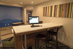 A hotel room with a desk, chair, computer, and a colorful abstract wall art. - Holiday Inn Express & Suites Dayton Southwest by IHG (Dayton)