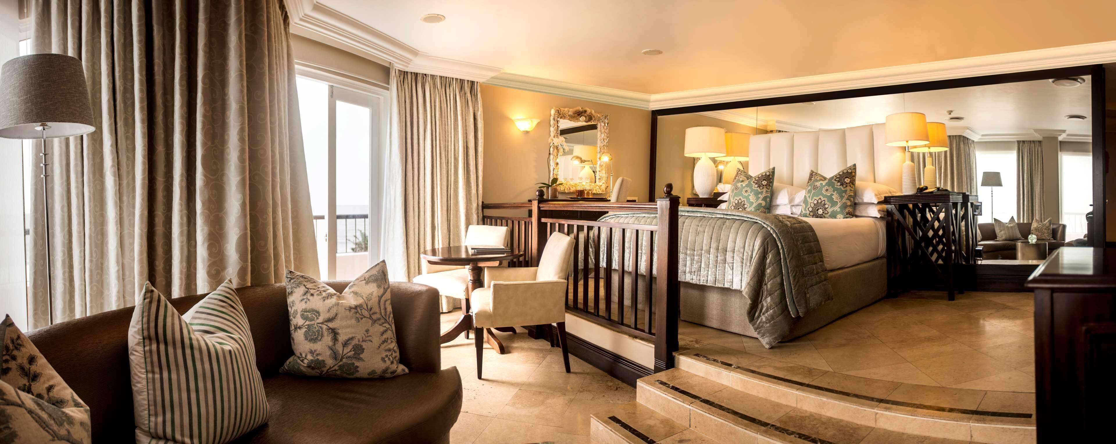 A hotel room with a bed, a sofa, a chair, a desk, and a mirror.