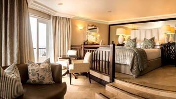 A hotel room with a bed, a sofa, a chair, a desk, and a mirror.