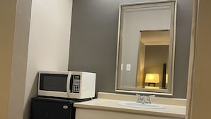 A compact bathroom with a microwave, sink, and mirror. - Tourist Inn (Absecon)