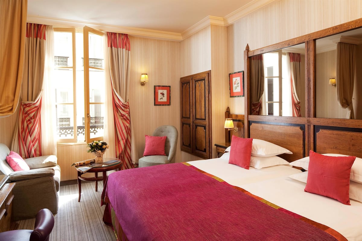 Una habitación de hotel con una cama grande, una silla, una mesita y un espejo.