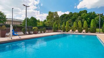 Relax by the serene pool surrounded by lush greenery and lounge chairs.