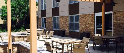 An outdoor patio area with stone walls, wooden furniture, and a pergola structure.